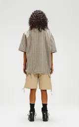Camisa oversize de manga corta con cuello abierto y estampado a rayas verticales en tonos verde y beige.