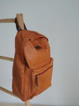 Mochila de cuero color marrón con forro de lino y cierres de bronce. Tiene un compartimento interno acolchado para computadora portátil.