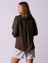 Camisa blanca de lyocell marca Cyrus, con cuello con solapa, abertura central con botones, mangas largas regulables con presilla y botón, y bolsillos delanteros aplicados.