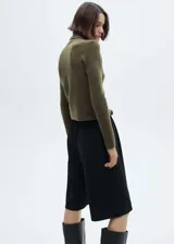 Sweater color beige de tejido de punto con cuello alto y mangas largas.