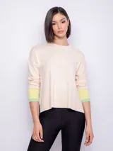 Sweater de punto color crema, con aberturas laterales y puños a rayas verde y amarillo.