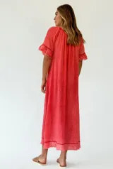 Vestido midi color coral, de textura arrugada, con escote redondo, mangas cortas con volados y ruedo con flecos.