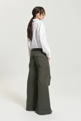 Pantalón de gabardina color verde militar, de corte ancho y tiro alto, con tablas a la altura de la rodilla y bolsillos plaqué en la espalda.