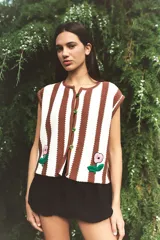 Chaleco tejido a rayas verticales marrones y celestes, con bordado artesanal de una flor en el frente y cierre con botones.