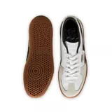 Zapatillas de cuero y gamuza en combinación de colores blanco y negro, con suela de goma color marrón.