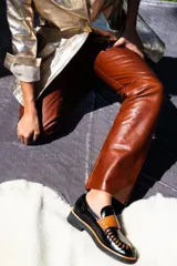 Mocasín de diseño único en colores negro, camel y dorado, con detalles de costura.