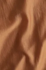 Pollera midi color marrón, de tejido transparente en mezcla de lyocell, tiro alto, bajo recto, tajo trasero y viso corto.