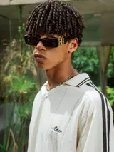 Chomba de tejido de punto cerrado color blanco, con cuello polo y mangas cortas. Presenta un bordado sutil en el frente y tres franjas negras en los hombros.