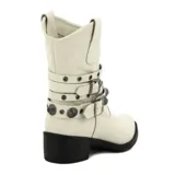 Bota de media caña color blanco con taco bajo y punta fina. Presenta tres tiras horizontales con hebillas y apliques metálicos.