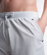 Bermuda deportiva gris con short de compresión negro incorporado, cintura elástica con cordón ajustable y bolsillos laterales con cremallera.