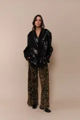Pantalón negro con detalles brillantes y corte amplio.