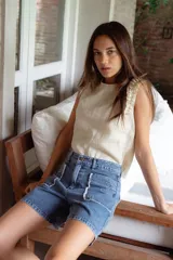 Short de denim azul de corte relajado y cintura media, con terminación deshilachada en los bordes y detalles de costura y apliques de denim en los bolsillos frontales.