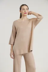 Conjunto de sweater y pantalón color beige con brillo metalizado. El sweater es holgado, de mangas 3/4 y cuello redondo. El pantalón es de corte palazzo.