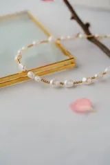 Gargantilla de perlas de agua dulce con detalles dorados en acero quirúrgico con baño de oro 18k.