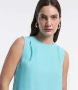 Blusa sin mangas color celeste, de crepé, con cuello redondo, pliegues en uno de los hombros y cierre trasero por cremallera con detalle de aro en el tirador.