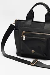 Cartera negra de nylon con diseño compacto y funcional. Cuenta con asas cortas y correa regulable desmontable para llevar al hombro o cruzada, además de múltiples bolsillos con cierre y detalles dorados.