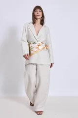 Blazer color crema de lino con corte clásico, solapas de muesca y cierre cruzado con un botón. Incluye un pañuelo de seda estampado atado a la cintura.