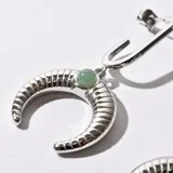Aros colgantes plateados con forma de media luna texturizada y detalle de piedra verde.