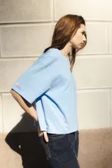 Remera blanca de algodón con cuello redondo y mangas cortas. Presenta un bordado del sol de la bandera uruguaya en el pecho.