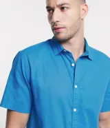 Camisa color beige claro de lino y algodón, corte comfort, manga corta, cuello camisero, cierre con botones y sin estampa.