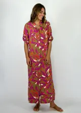 Vestido largo tipo camisero con estampado floral en tonos fucsia, blanco y naranja sobre fondo verde oliva.