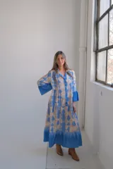 Vestido largo celeste con estampado tie-dye en tonos beige, corte amplio y mangas 3/4 acampanadas.