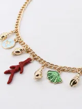 Collar dorado con cadena de eslabones y dijes colgantes con motivos marinos: conchas, estrellas de mar, abanicos y una rama de coral roja.