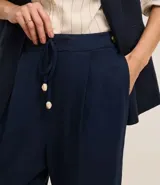 Pantalón fluido color verde oliva confeccionado en viscolino, con cintura elástica, lazo, pliegues y bolsillos.