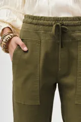 Pantalón tipo babucha color verde militar, confeccionado en gabardina elastizada, con ajuste en tobillos y cintura regulable con cordón a tono. Cuenta con bolsillos diagonales en el frente y bolsillos con solapa y botón en la parte trasera.