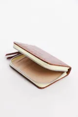Billetera de cuero vacuno con cierre metálico, compartimientos para tarjetas y billetes, dimensiones 15 x 10 cm.