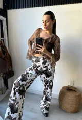 Pantalón de jean con estampado animal print de vaca en tonos marrón y blanco, de corte recto.