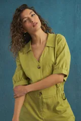 Mono corto color ladrillo con cuello camisero, mangas cortas con puños elásticos, cintura elastizada y bolsillos laterales.