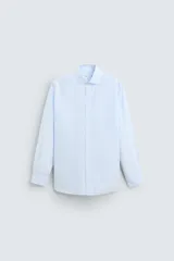 Camisa celeste a rayas verticales, de corte regular fit, cuello italiano, manga larga con puños abotonados y cierre frontal con botones.