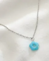 Gargantilla plateada con dije de flor celeste.