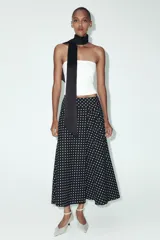Falda midi negra con estampado de lunares blancos, de tiro alto y corte evasé.