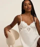 Camisón corto blanco de microfibra con breteles finos regulables y detalle de encaje floral en el busto.