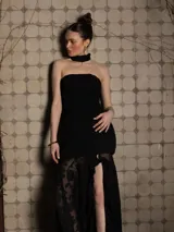 Vestido negro strapless con cuerpo fruncido y falda con tajo lateral y volados. Incluye choker al tono.
