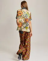 Pantalón fluido de viscosa con estampado geométrico en tonos rojo, naranja, amarillo y verde. Presenta cintura elástica y detalle de denim en los laterales.