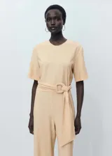 Mono color beige de viscosa y poliamida, con cuello redondo, manga corta, cinturón con hebilla y cierre de botón en la parte posterior.