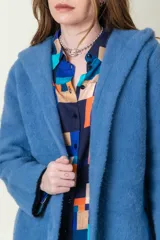 Tapado largo de paño azul con capucha y bolsillos laterales.