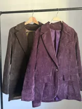 Blazer de corderoy con corte oversized, solapas de muesca y un solo botón frontal. Presenta bolsillos de parche en la parte delantera. Disponible en color marrón chocolate y morado merlot, ambos con forro interior.