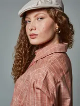 Camisa de manga larga color ladrillo con rayas blancas, confeccionada en lino. Tiene cuello clásico, cierre frontal con botones y bolsillo de parche en el pecho.