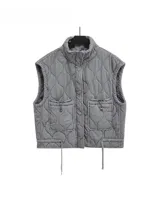 Chaleco gris con diseño acolchado, cuello alto, cierre frontal con cremallera, dos bolsillos delanteros con solapa y ajuste con cordones en el bajo.