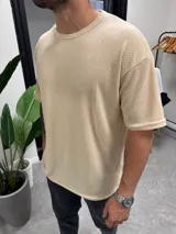 Remera color beige de punto símil tejido, corte holgado y mangas cortas.