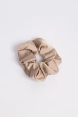 Gomita para el pelo tipo scrunchie de tela color beige.
