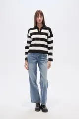 Sweater de tejido de punto, holgado, con rayas horizontales anchas en blanco y negro. Presenta cuello polo con escote en V y mangas largas.