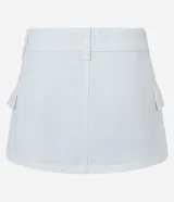 Minifalda blanca de sarga con cintura baja, trabillas, bolsillos cargo y cinturón con hebilla cuadrada metálica.