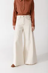Pantalón jean de corte wide leg color crudo, con cintura alta, bolsillos delanteros y traseros, y ruedo desflecado.