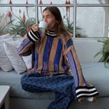 Sweater de punto oversize a rayas verticales rosas y bordó, con cuello alto y puños con ribete celeste.