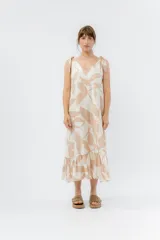 Vestido largo color crema con estampado de hojas color beige, breteles finos con lazos y volado en el ruedo.